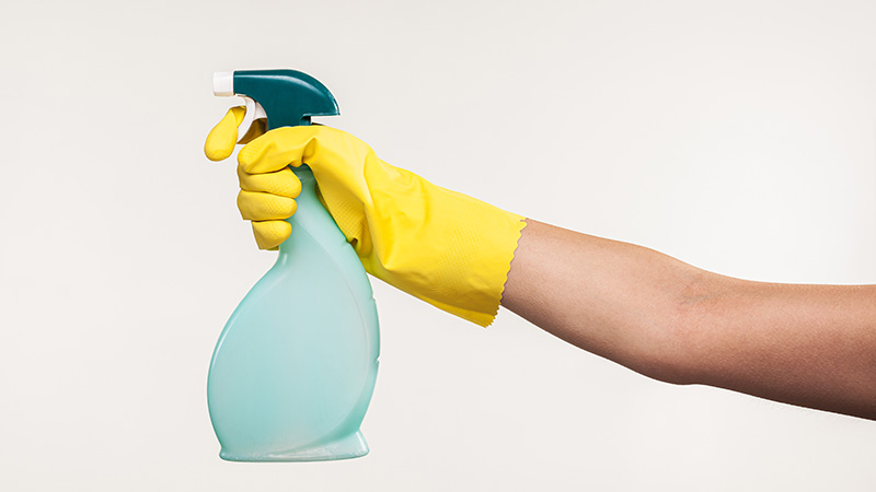 mano con guanto giallo che impugna uno spruzzino